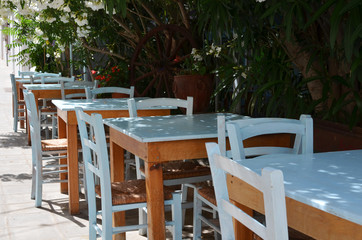Fototapeta na wymiar Wooden table and blue chairs on terrace in restaurant. Patio restaurant with empty sitting place.