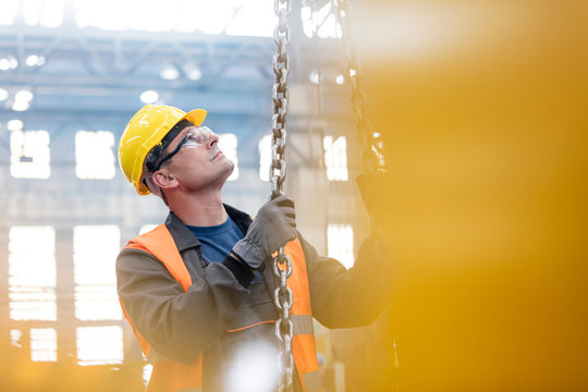 Steel worker holding chain in factory