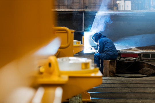 Welder using welding torch in steel factory