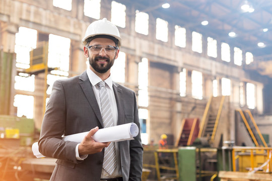 Portrait smiling manager with blueprints in steel factory