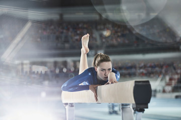 Female gymnast practicing on balance beam in arena