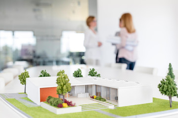 Female architects talking behind building model