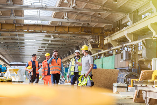 Steel workers walking and talking in factory