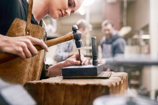 Jeweler using hammer in workshop