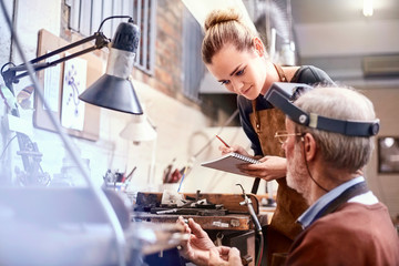 Jeweler teaching apprentice in workshop