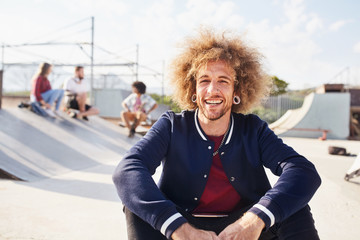 Portrait confident young man with afro at sunny skate park