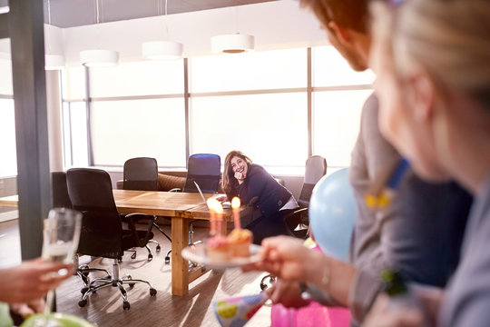 Business people surprising businesswoman birthday cupcakes in conference room