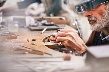 Male jeweler using headband magnifier making jewelry in workshop