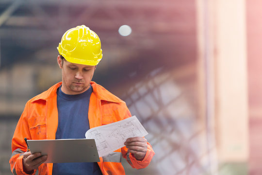 Steel Worker Reviewing Blueprints In Factory