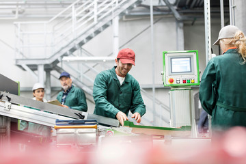 Smiling worker at conveyor belt in food processing plant