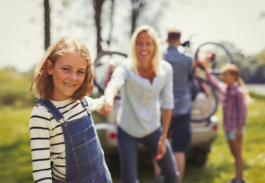 Portrait smiling mother and daughter holding hands outside car