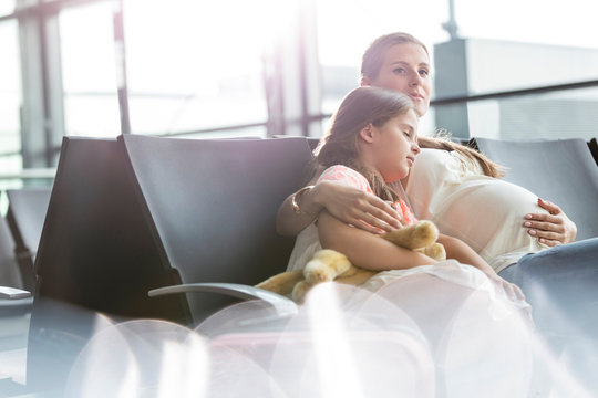 Pregnant mother sleeping daughter waiting in airport departure area