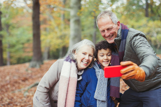 Grandparents and grandson taking selfie in autumn woods