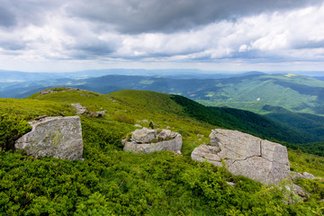 beautiful mountain landscape in summer. rocks on the grassy alpine meadows rolling into distance. clouds on the sky above horizon