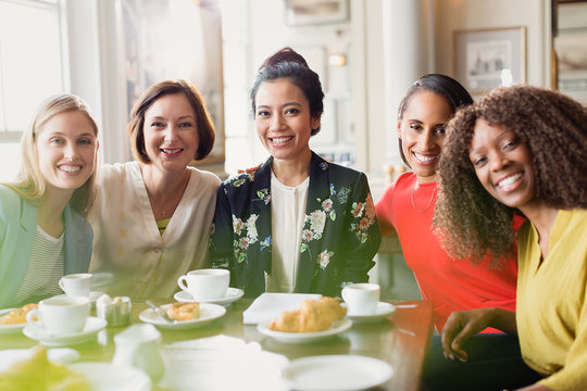 Portrait Smiling Women Friends Drinking Coffee At Restaurant Table