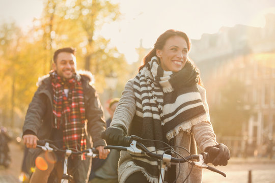 Smiling young couple bike riding on urban autumn street