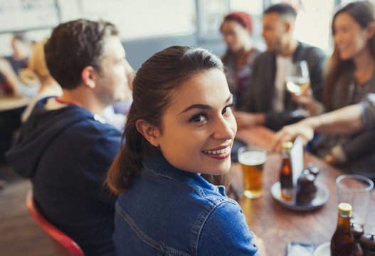 Portrait Smiling Woman Drinking Beer With Friends At Table In Bar