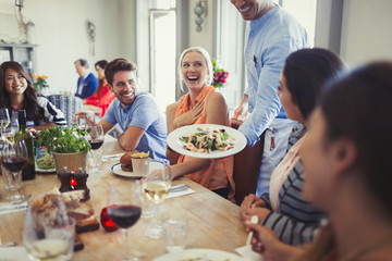 Waiter serving salad to woman dining with friends at restaurant table