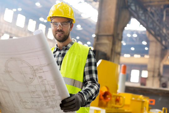 Portrait smiling engineer with blueprints ins steel factory