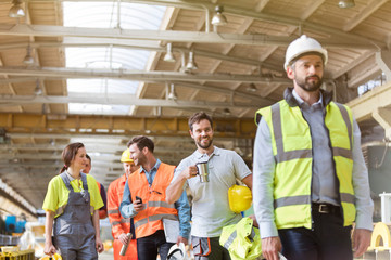 Steel workers talking and walking on coffee break in factory