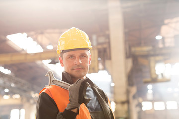 Portrait confident steel worker holding large wrench in factory