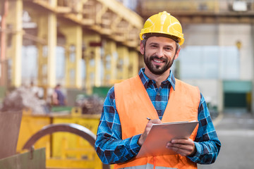 Portrait smiling steel worker with clipboard in factory