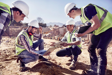 Construction workers engineers using digital tablets at sunny construction site
