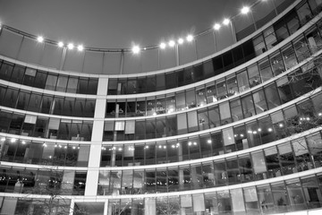 Night architecture - building with glass facade. Business district. Concept of economics, financial. Photo of commercial office building exterior. Abstract image of office building. Black and white.