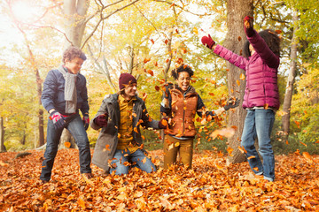 Playful young family throwing leaves in autumn woods