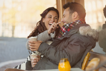 Playful young couple with milkshake at sidewalk cafe