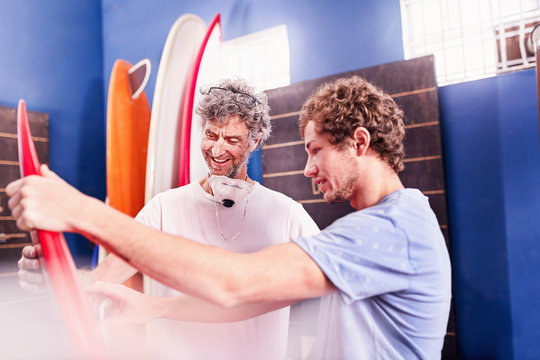 Men making and discussing surfboards in workshop - Powered by Adobe