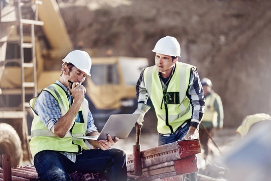 Foreman and construction worker using laptop at construction site
