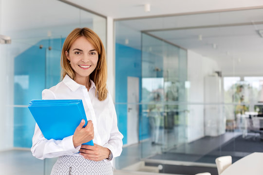 Portrait smiling businesswoman holding folders in conference room