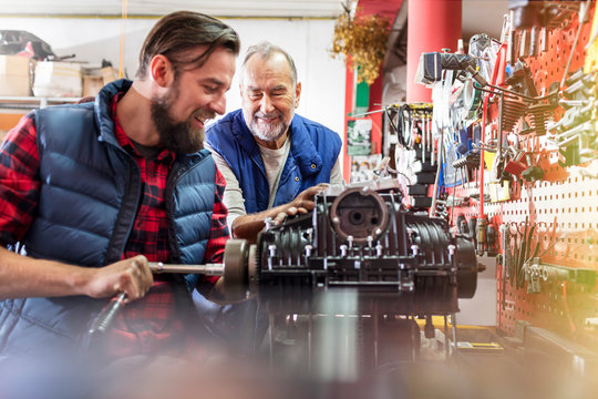Male motorcycle mechanics repairing engine in workshop