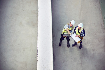 Construction worker engineer with laptop talking at construction site