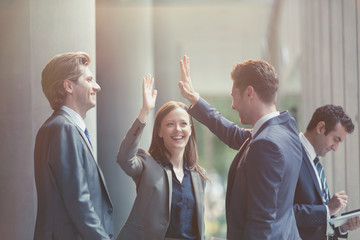 Business people high-fiving in office lobby