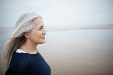 Pensive senior woman looking away on winter beach