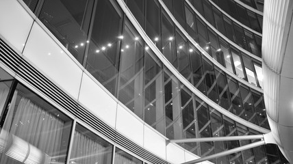 Obraz premium Night architecture - building with glass facade. Business district. Concept of economics, financial. Photo of commercial office building exterior. Abstract image of office building. Black and white.