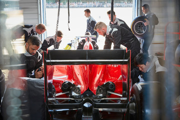 Pit crew preparing formula one race car in repair garage