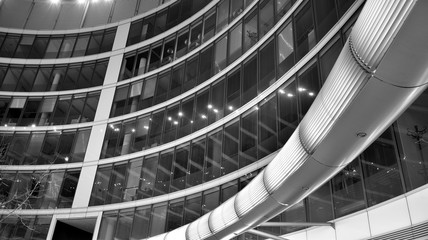 Night architecture - building with glass facade. Business district. Concept of economics, financial. Photo of commercial office building exterior. Abstract image of office building. Black and white.