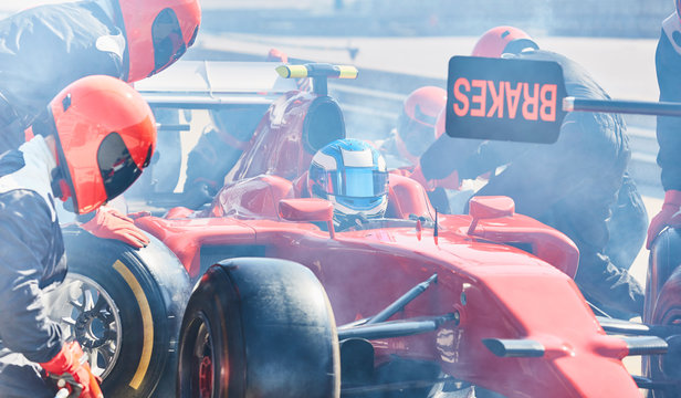 Pit crew replacing tires on formula one race car in pit lane