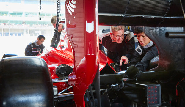 Pit crew mechanics examining race car in repair garage
