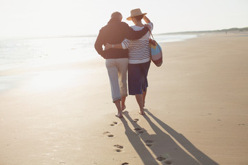 Mature couple hugging and walking on sunny beach
