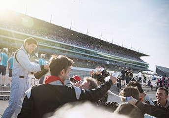 Formula one racing team driver spraying champagne, celebrating victory on sports track