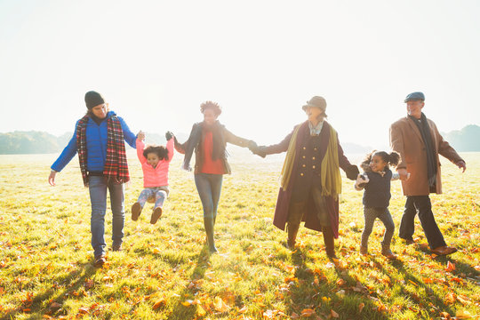 Playful multi-generation family walking in sunny autumn park grass