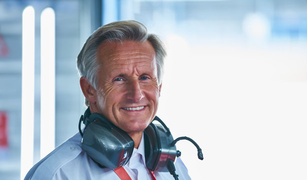 Portrait smiling formula one racing manager with headphones