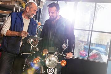 Motorcycle mechanic discussing paperwork with customer in shop