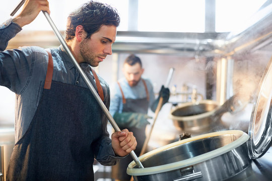 Focused male coffee roaster checking tank