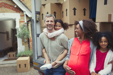 Portrait smiling pregnant multi-ethnic young family moving into new house