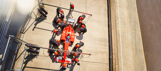 Overhead pit crew working on formula one race car in pit lane